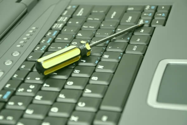 Screwdriver laying on top of a laptop keyboard
