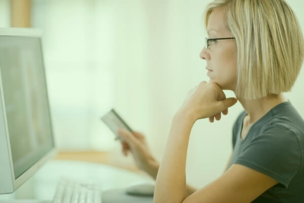 Woman holding a credit card while looking at a computer screen