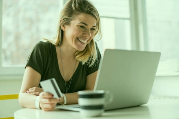Young woman holding a credit card in front of a laptop