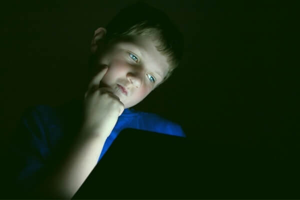 Elementary school aged boy looking at a tablet device in the dark